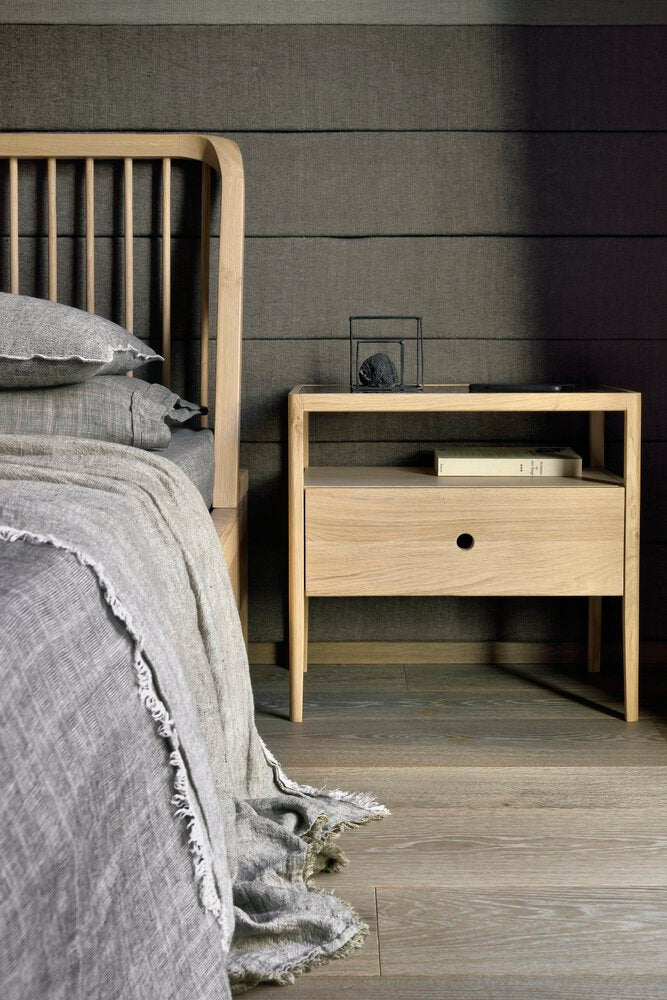 Bedroom with wooden bed and nightstand against a gray wall.