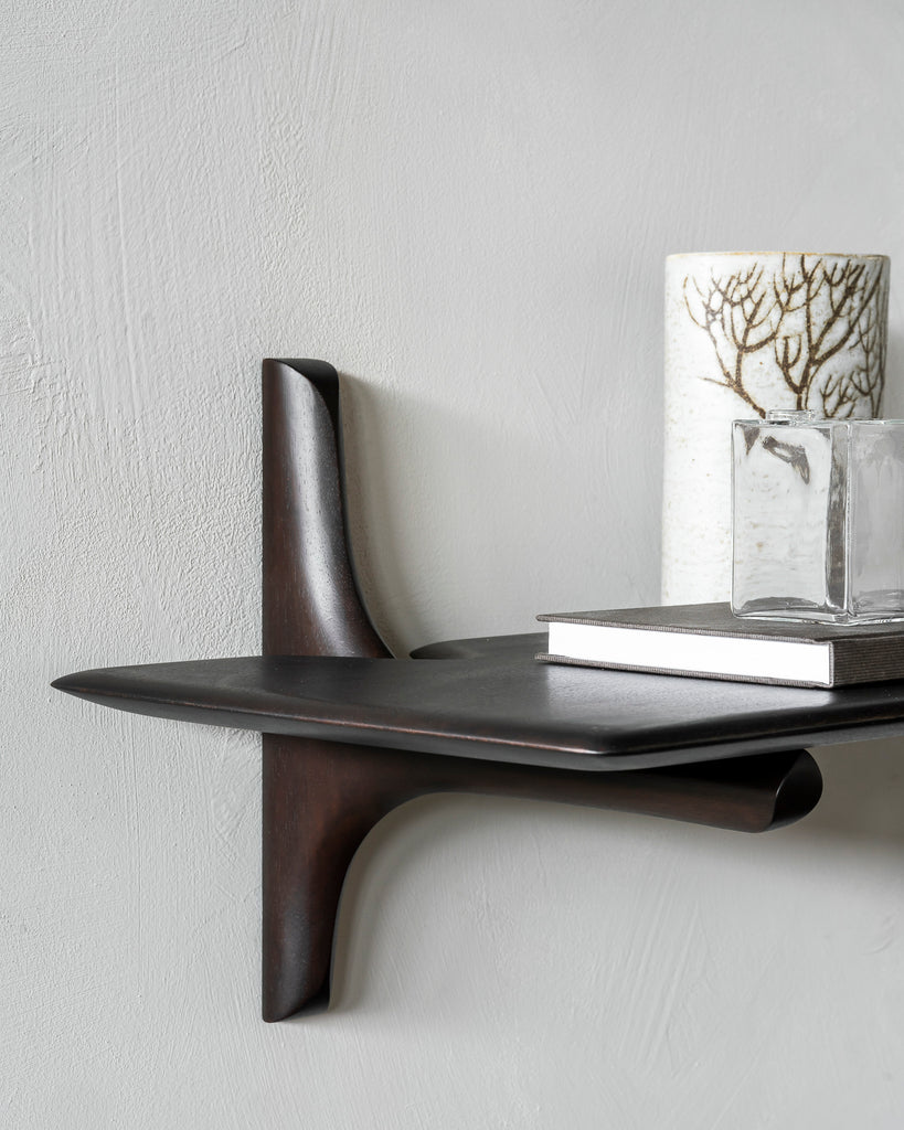 Modern wall shelf with decorative items against a light gray wall