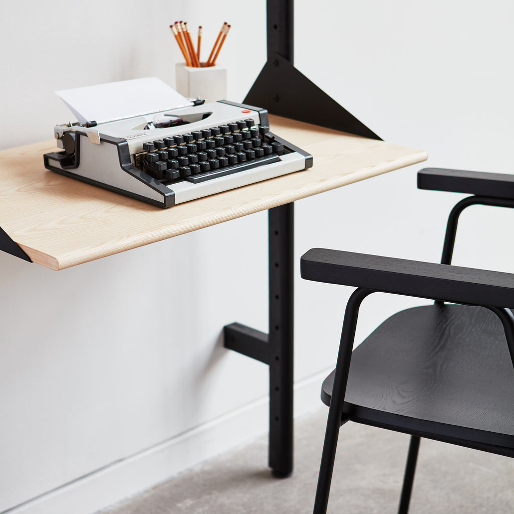 Typewriter on a wooden desk with a chair in the foreground