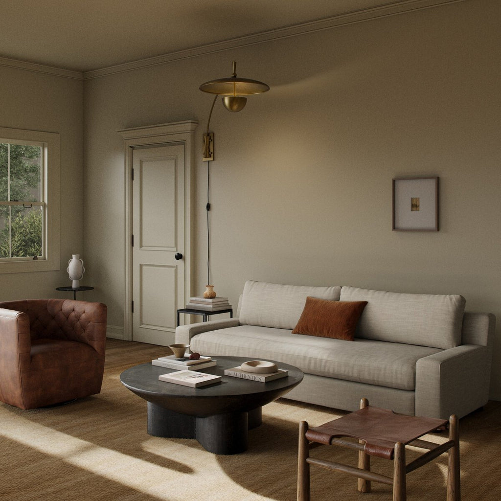 Beige sectional sofa with a matching ottoman on a patterned rug.