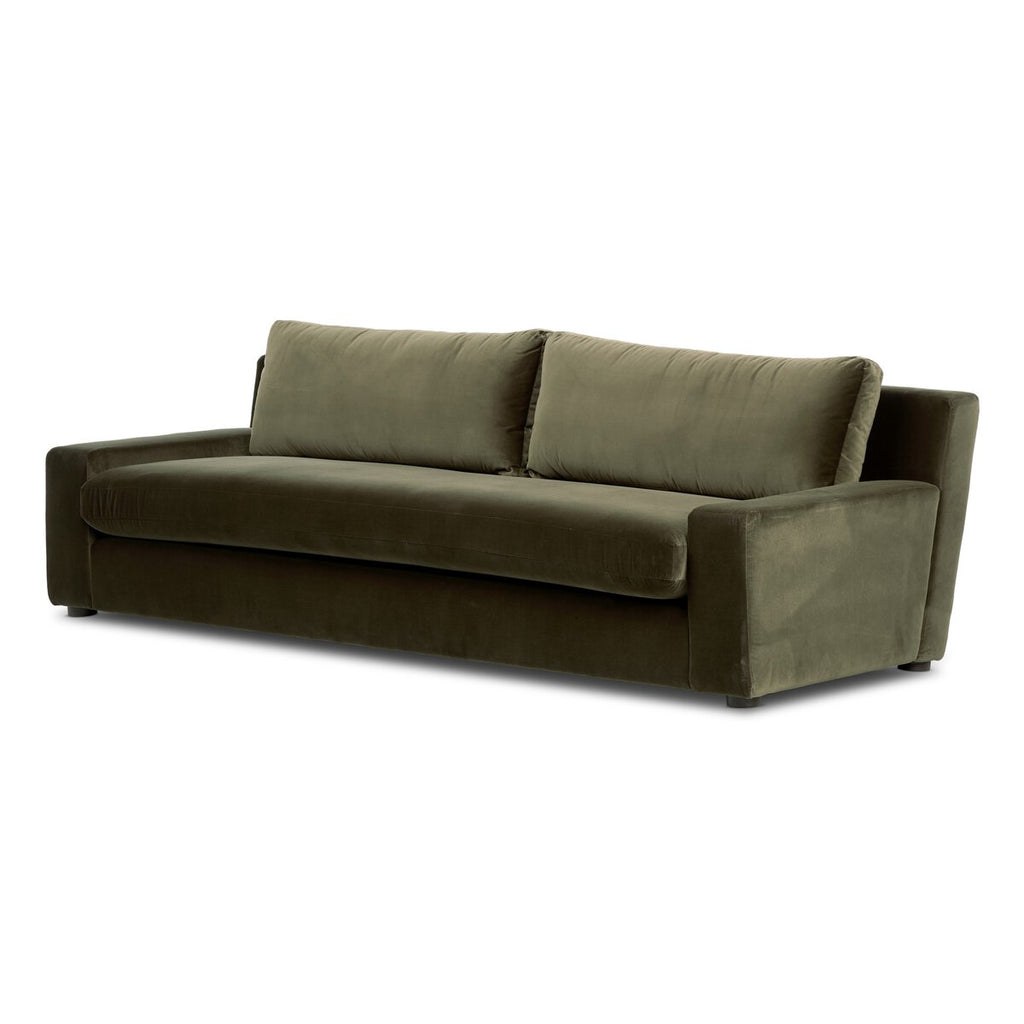 Green sectional sofa on a patterned rug with wooden floor