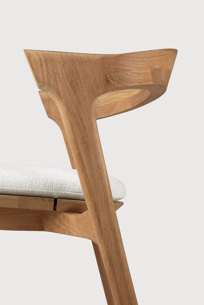Wooden chair with a white cushion on a light gray background