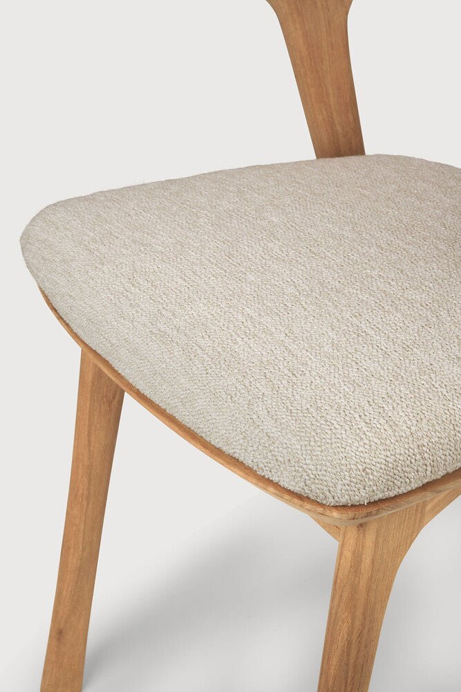 Close-up of a wooden chair with a beige cushioned seat on a white background