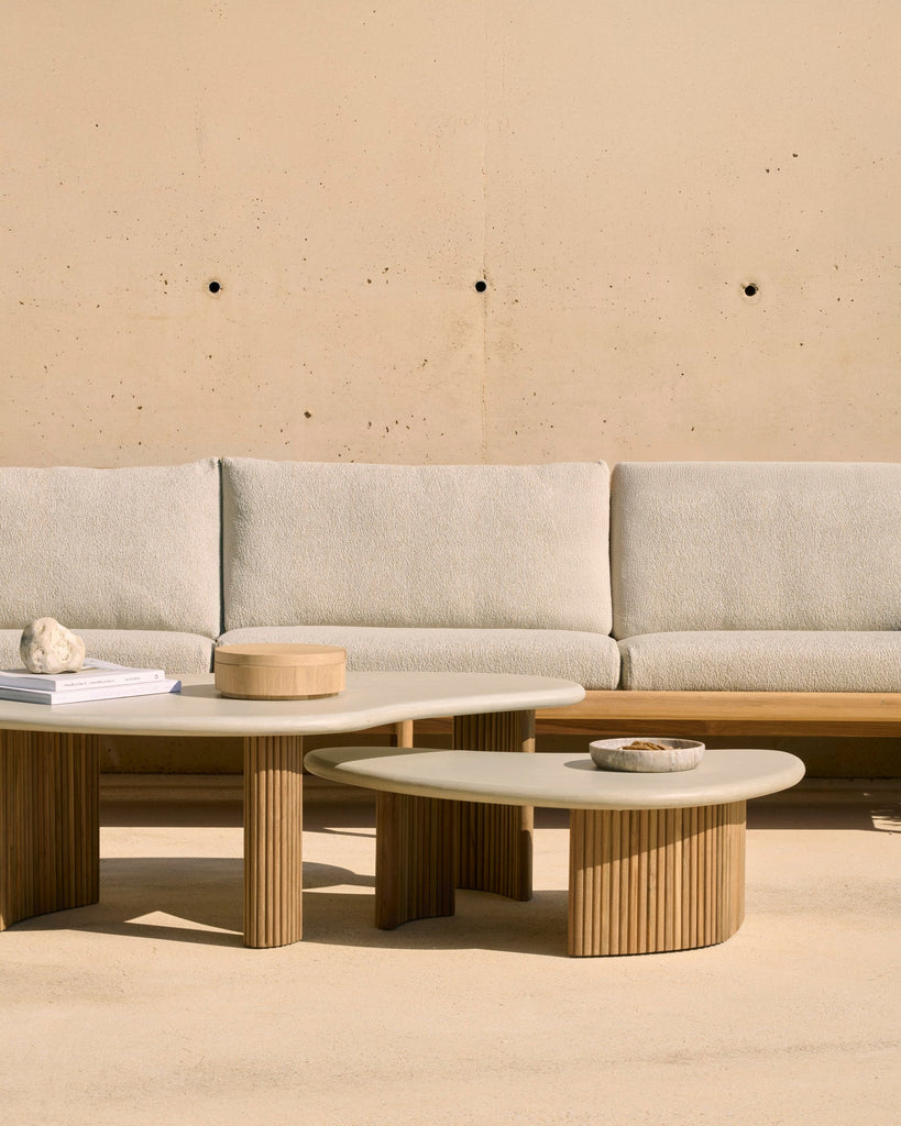 Light gray sofa with two round coffee tables against a beige wall.