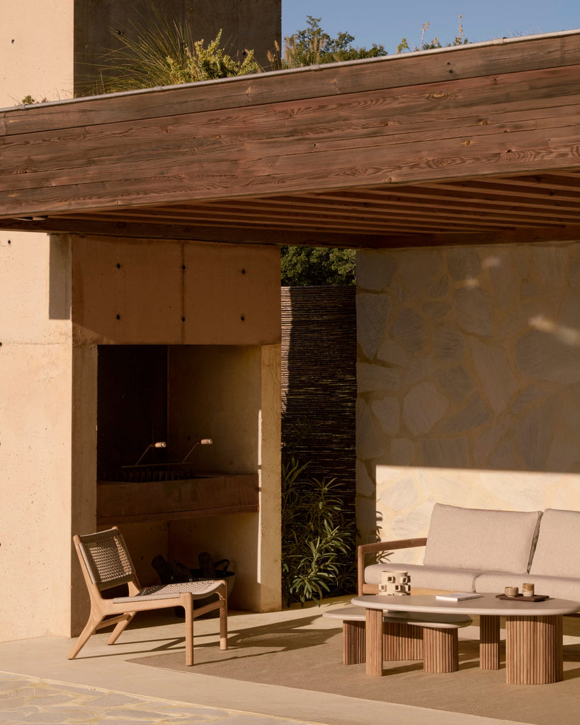 Outdoor patio area with furniture and a fireplace under a wooden overhang.