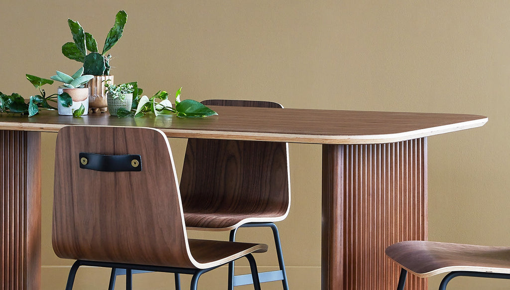 Wooden dining table with chairs against a beige wall