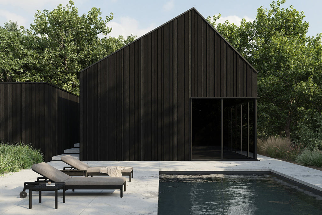Modern black house with lounge chairs by a pool surrounded by greenery