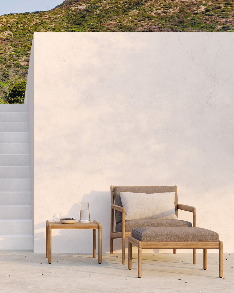 Outdoor furniture set with a chair and table against a white wall with greenery.