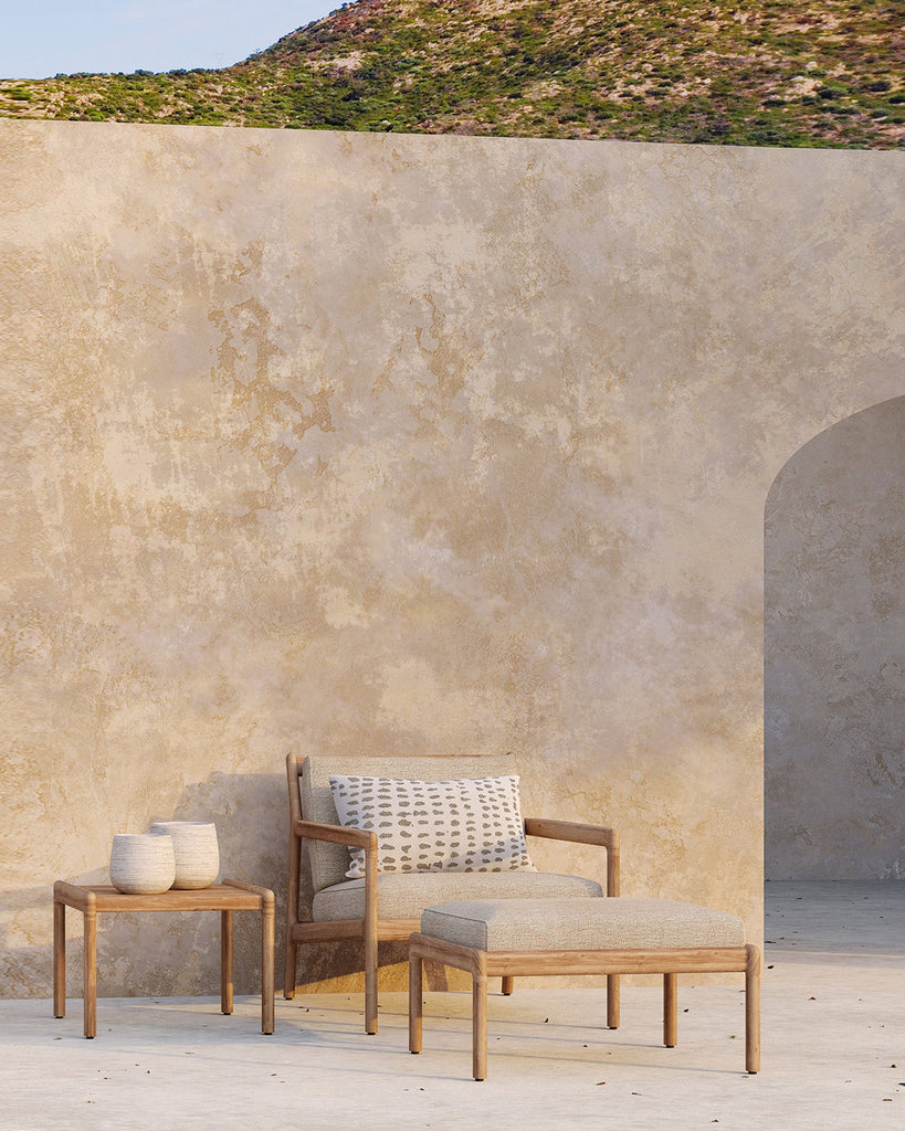 Outdoor furniture set against a textured wall with a mountainous background
