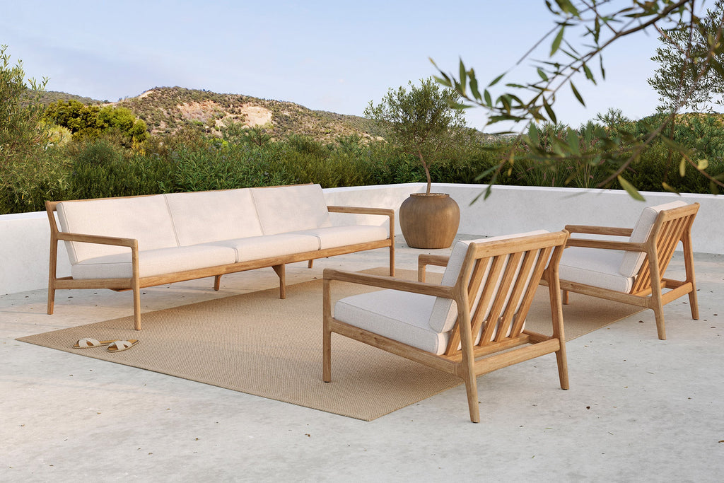 Outdoor furniture set with a sofa and chairs on a patio with a scenic background.