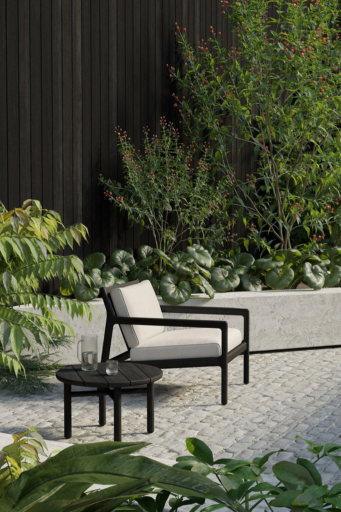 Outdoor furniture set with black frame and white cushions in a garden setting.